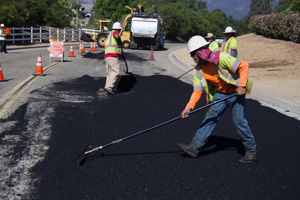 Workers putting down asphalt on road.